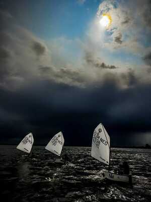 3 zeilboten op het water met donkere luchten